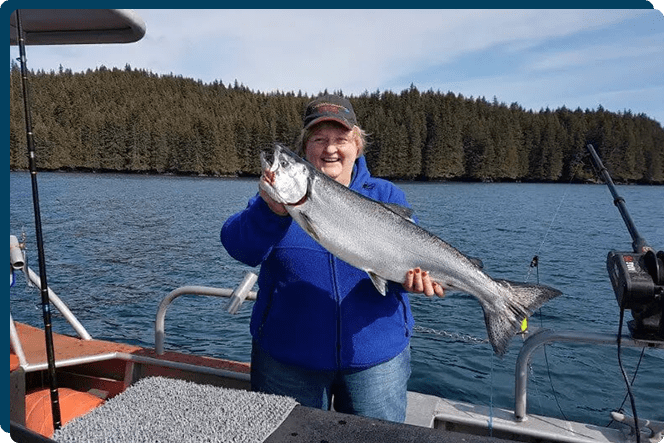 A woman holding a fish on top of a boat.