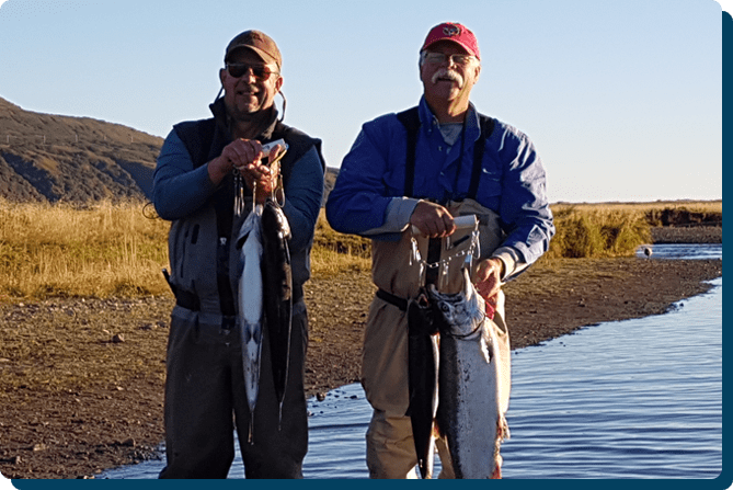 Two men standing next to each other holding fish.