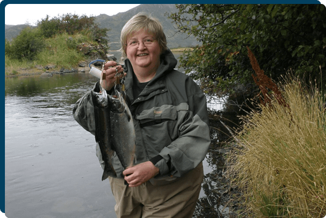 A woman holding a fish in her hand.