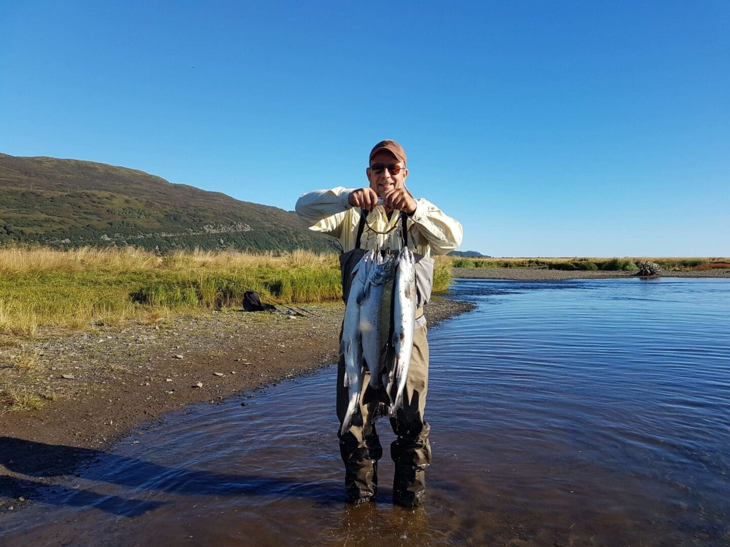 A man standing in the water holding a fish.